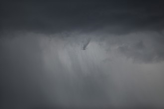 Aircraft breaks through cloud cover and drags a visible wake of vortices behind it