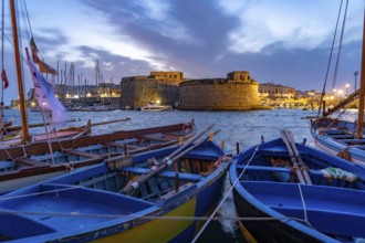 Typical fishing boats and the Castello di Gallipoli fortress at dusk, Gallipoli, Apulia, Italy