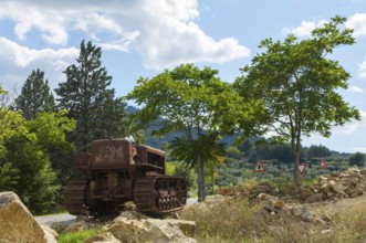 Old, heavily rusted bulldozer for road construction stands abandoned on rocks, industrial relic