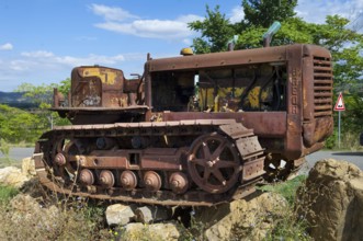 Old, heavily rusted bulldozer for road construction stands abandoned on rocks, industrial relic