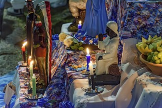 Altar with Umbanda deities and objects of worship lit by candles at night, Belo Horizonte, Minas