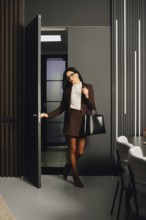 A business professional confidently enters a contemporary office space during the evening. Dressed