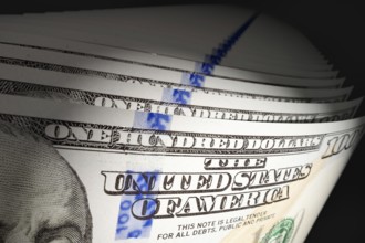 Spot lit abstract close-up angle of U.S. 100 dollar bills isolated on a black background