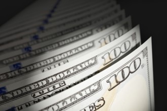 Spot lit abstract close-up angle of U.S. 100 dollar bills isolated on a black background