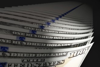 Spot lit abstract close-up angle of U.S. 100 dollar bills isolated on a black background