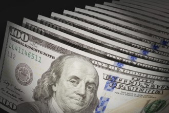 Spot lit abstract close-up angle of U.S. 100 dollar bills isolated on a black background