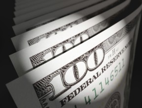 Spot lit abstract close-up angle of U.S. 100 dollar bills isolated on a black background