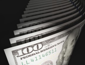 Spot lit abstract close-up angle of U.S. 100 dollar bills isolated on a black background