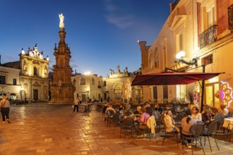 Restaurant in Piazza Salandra with the Guglia dell'Immacolata column at dusk, Nardo, Apulia, Italy