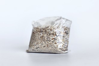 Small plastic bag containing ash of a pet cat after cremation on white background