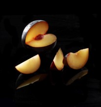 Plum, plum slices against a black background