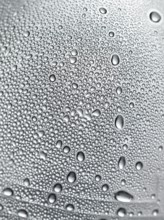 Drops of water on plastic bottle, neutrally illuminated, detailed view