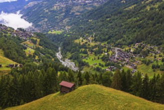 Small mountain hut on a green hill, with the villages of Mission and Saint Jean behind, Val