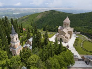 Historic monastery on a green hill surrounded by trees and towers, Bodbe Monastery, Sighnaghi,