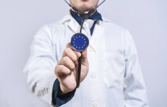 Doctor hands holding stethoscope with European Union flag. European Union health and care concept