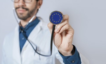 Doctor holding stethoscope with European Union flag. European Union health and care concept,