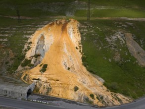 A hill with a distinctive orange rock formation next to a road with a bridge, aerial view, Bidara