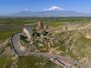 Historical church in front of majestic mountains, embedded in a green landscape with a wide sky,