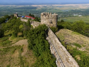 Stone castle wall with towers winding through a natural landscape of trees and fields, aerial view,