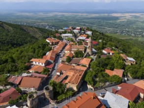 Surrounded by hills lies a picturesque village with tiled roofs and a church overlooking the