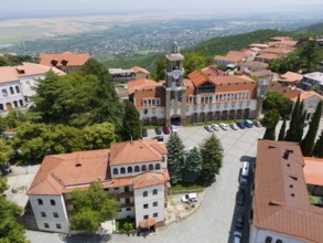 Square with a dominant tower and traditional buildings surrounded by green hills, aerial view,
