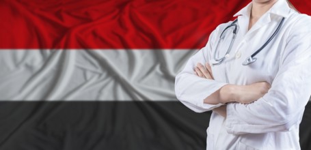 Doctor with crossed arms on Yemen flag. Yemeni health and care concept. Female doctor on Yemen flag