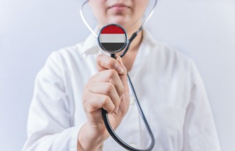 Female doctor holding stethoscope with Yemen flag. National health system of Yemen