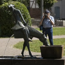 Man photographing the Münchhausen fountain by Bruno Schmitz with the halved horse, Bodenwerder,