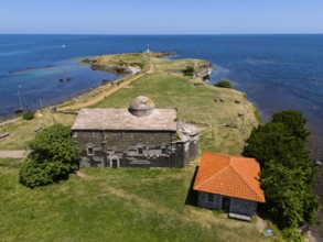 Aerial view of a historic church on the coast with neighbouring building and wide sea horizon,