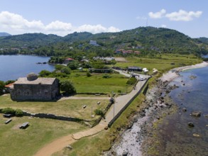 Panoramic view of a church along the coast surrounded by hills and water in a summer atmosphere,