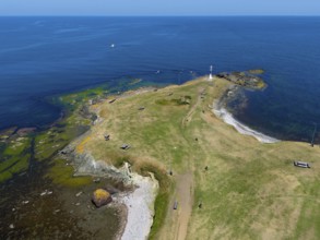 Aerial view of a small island with a lighthouse and green areas surrounded by the blue sea, aerial