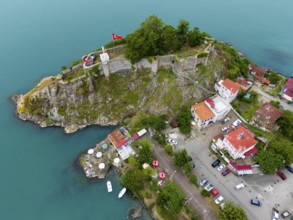 Aerial view of a castle by the sea with Turkish flag and surrounding buildings, aerial view,