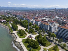 Densely built-up town with parks on the coast, surrounded by mountains and architecture with red