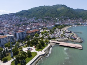Coastal town on a hill with dense buildings, parks and a promenade along the sea, aerial view,