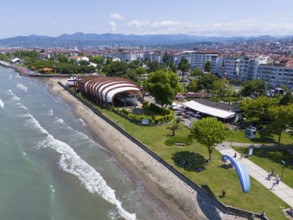 Aerial view of a coastal promenade with modern buildings and undulating beach sections, aerial