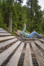Woman lying relaxed on a wooden bench in a wooded area, Mummelsee, Seebach, Ortenau district, Black