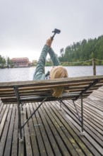 Woman lying on a bench by the lake and holding a camera, Mummelsee, Seebach, Ortenau district,