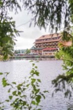 Building with terrace on a quiet lake, framed by leaves, Mummelsee, Seebach, Ortenau district,