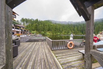View of a lake from a wooden footbridge with buildings in the background, Mummelsee, Seebach,