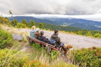 Group on a bench marvelling at the panorama over the mountain landscape with clouds in the sky,