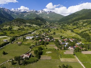 Vast landscape with villages and fields under a blue sky, framed by mountains, aerial view,