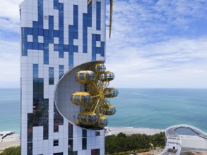 Modern building with futuristic design and golden gondolas on the coast with sea background, aerial