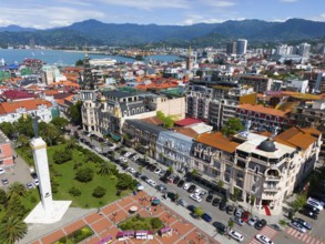 Historic buildings and central squares in a colourful coastal town with mountains, aerial view,