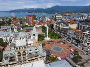 Historic architecture with large square, surrounded by mountains near the coast, aerial view,