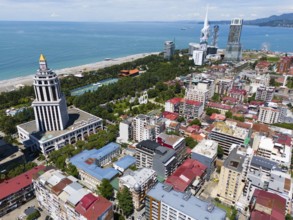 City centre with prominent tower and skyscrapers, sea and beach in the background, aerial view,