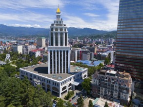 Tall building in a city with mountain backdrop and blue sky, aerial view, Sheraton Hotel, Batumi,