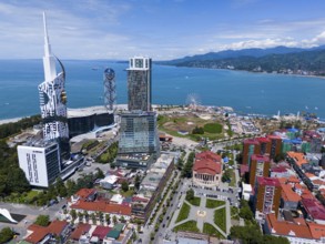 Modern high-rise buildings near the coast, blue sky and amusement park with Ferris wheel, aerial