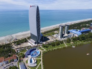 Unique building on the beach next to modern structures and sea, aerial view, Hotel Alliance