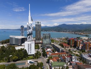 Modern high-rise buildings on the seashore with mountain panorama and clear sky, aerial view,