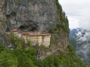 A mystical monastery in a misty rocky landscape, high above the green surroundings, aerial view,